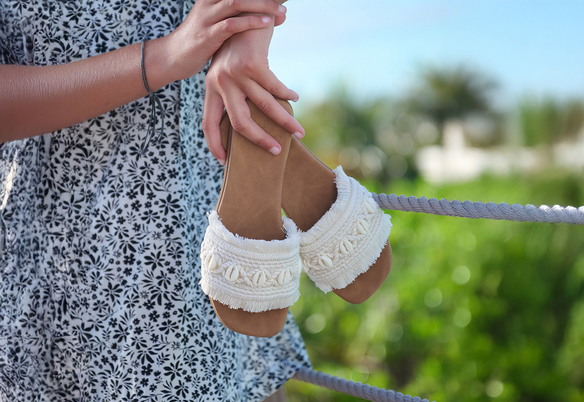 Arms holding crochet sandals from the brand Roxy. 